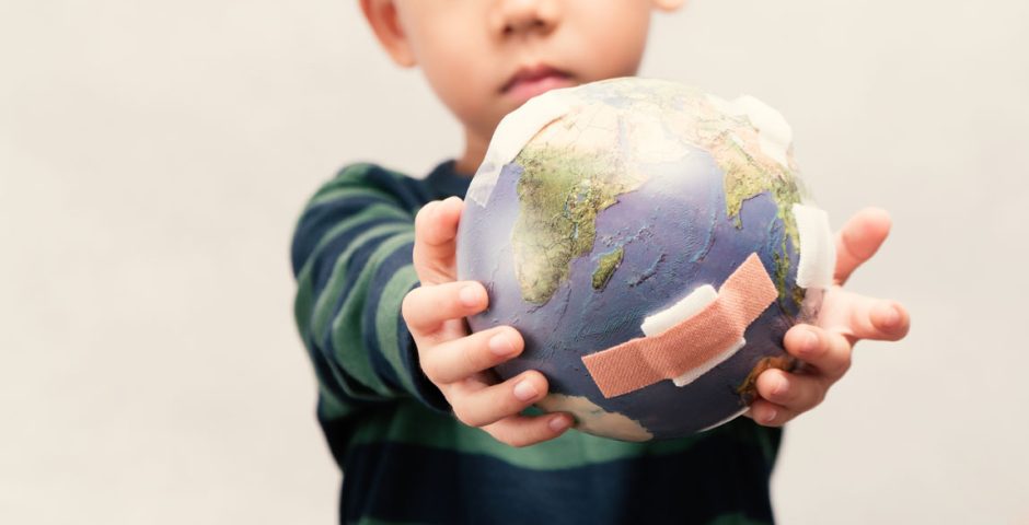 Ein Kind hält einen mit Pflastern verarzteten Globus